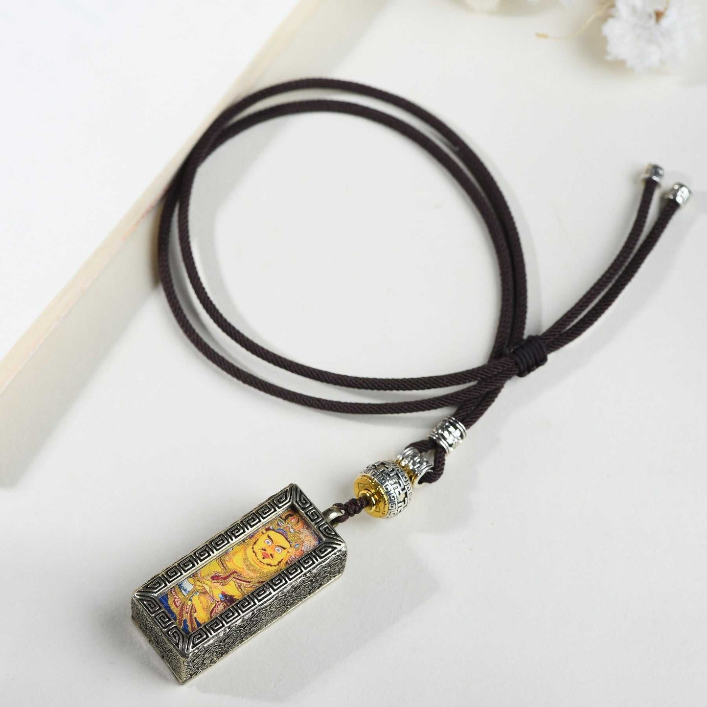 Tibetan-style Tang Kazakiram pendant with Yellow God of Wealth image on a black cord necklace.